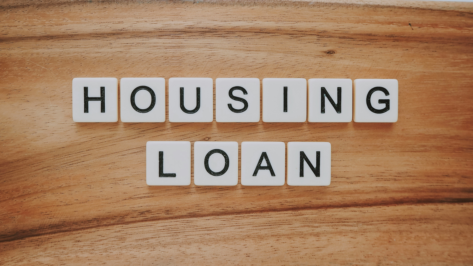 White scramble tiles that spell “housing loan” ontop of a wooden table