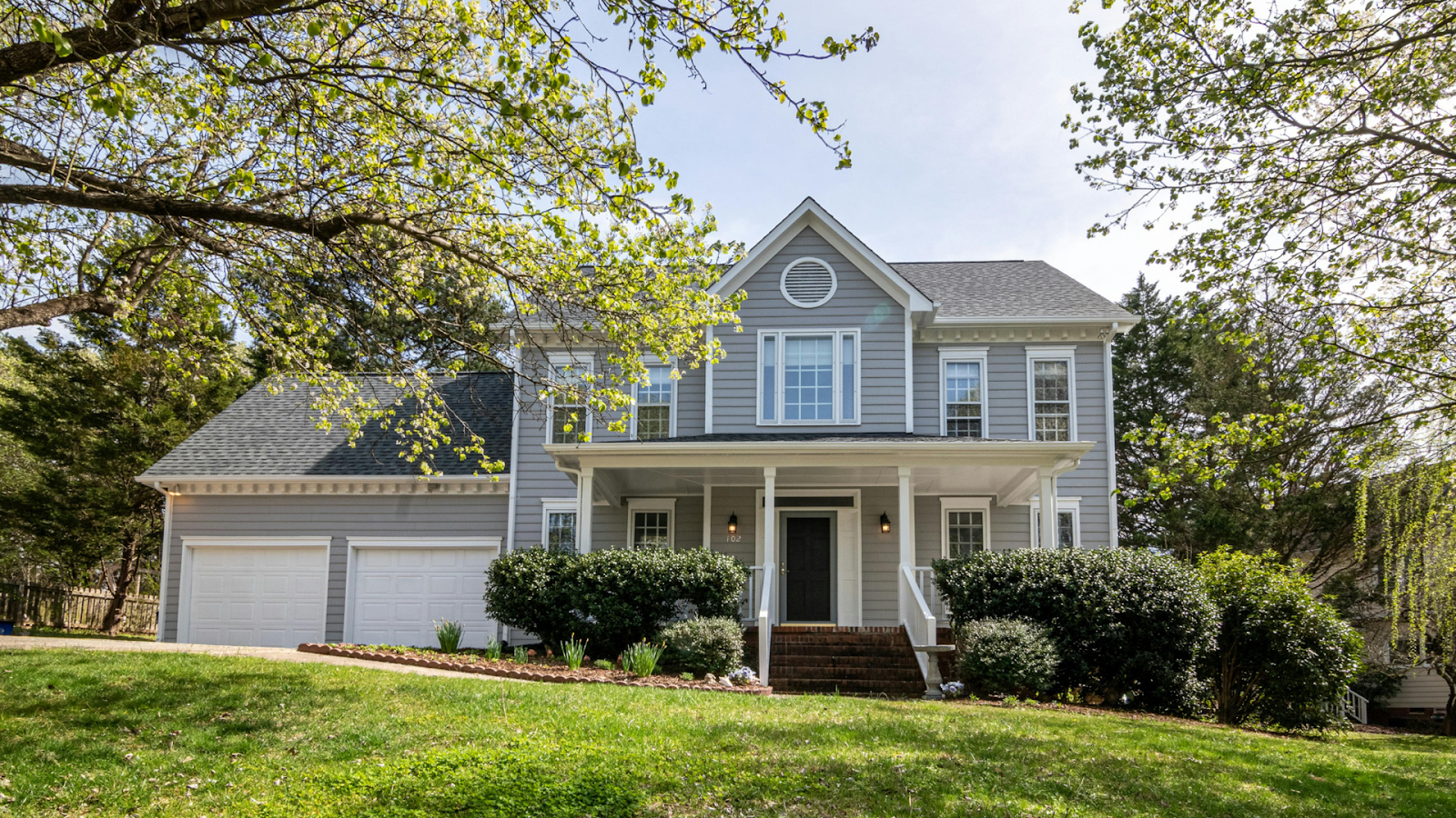 Gray three-story home with two-car garage and front porch