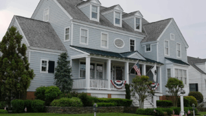 Pale blue three-story home with porch with white columns