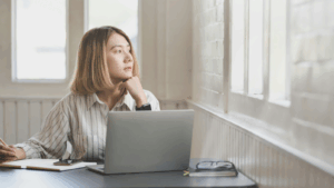 Woman peering out a window and writing on a notepad