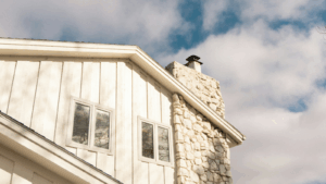 Wooden home with a white stone chimney and white trimmings